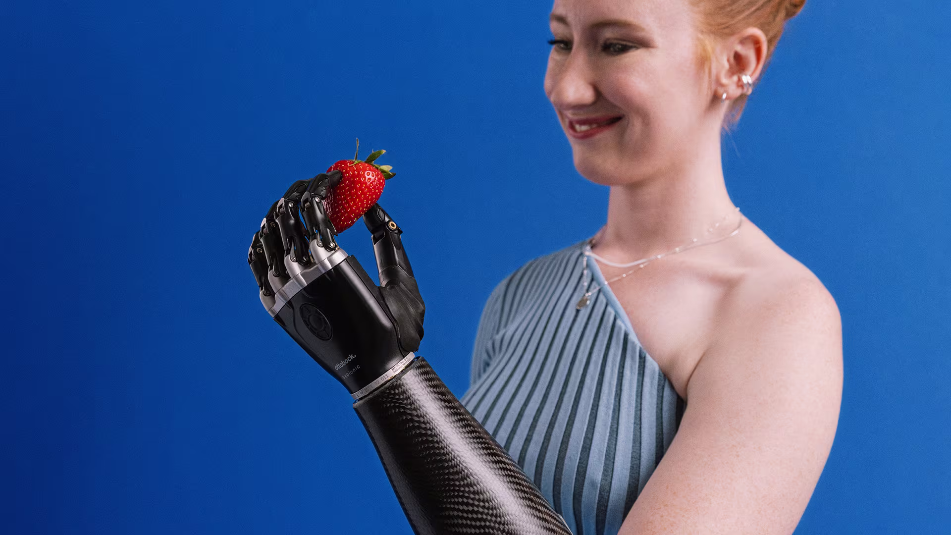 Enya holds a strawberry with her bebionic hand.