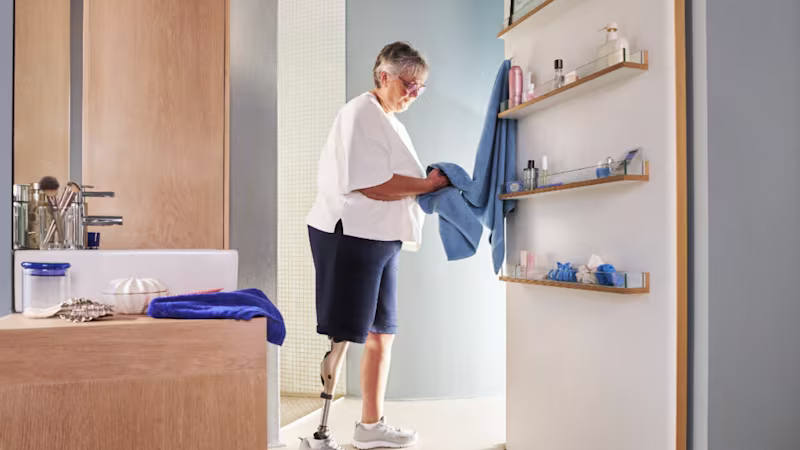 A woman using Genium x4 is in bathroom drying her hands with a towel
