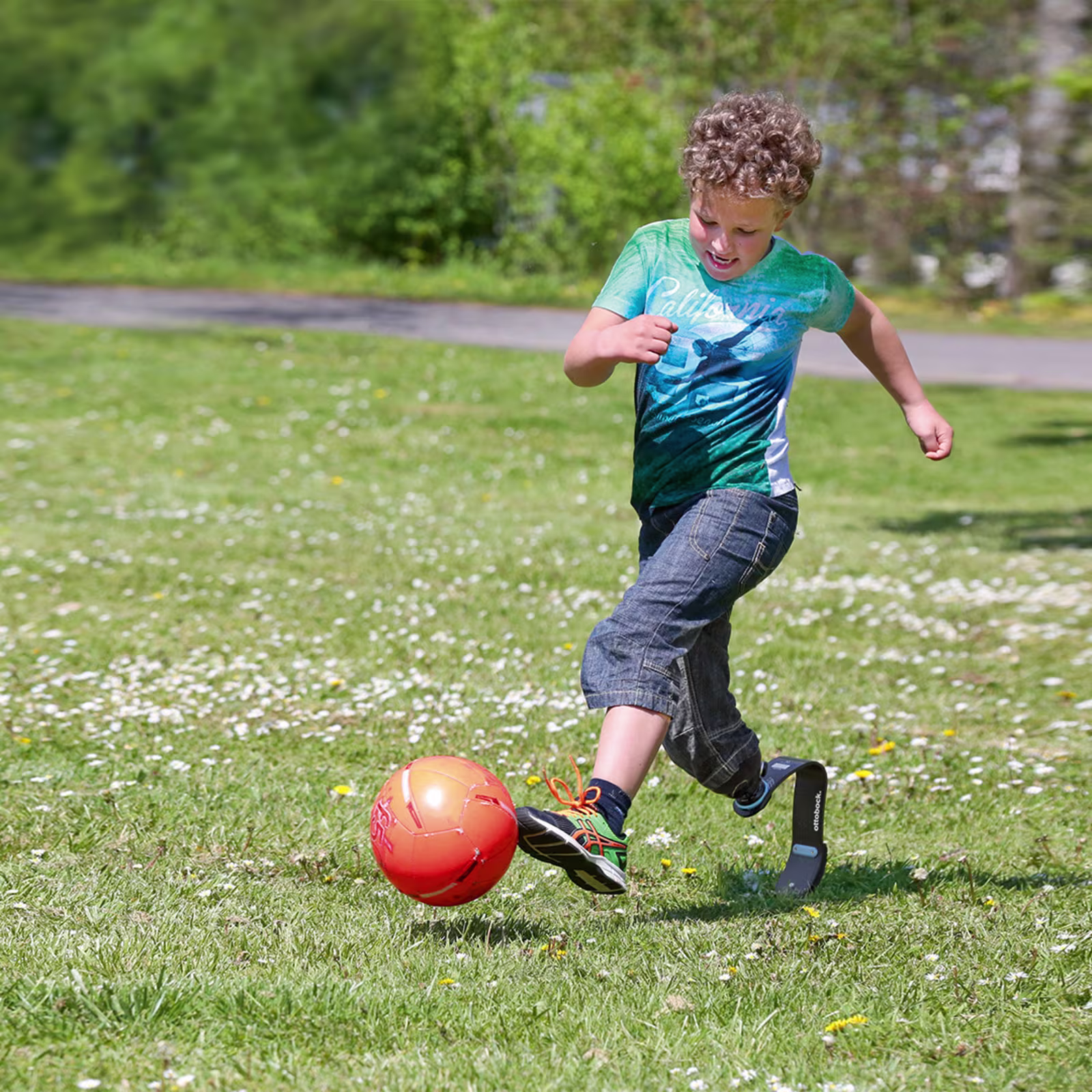 Un bambino con una protesi gioca a palla sul prato