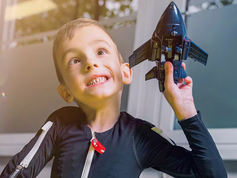 Exopulse Mollii Suit user Alexander playing with a toy aeroplane