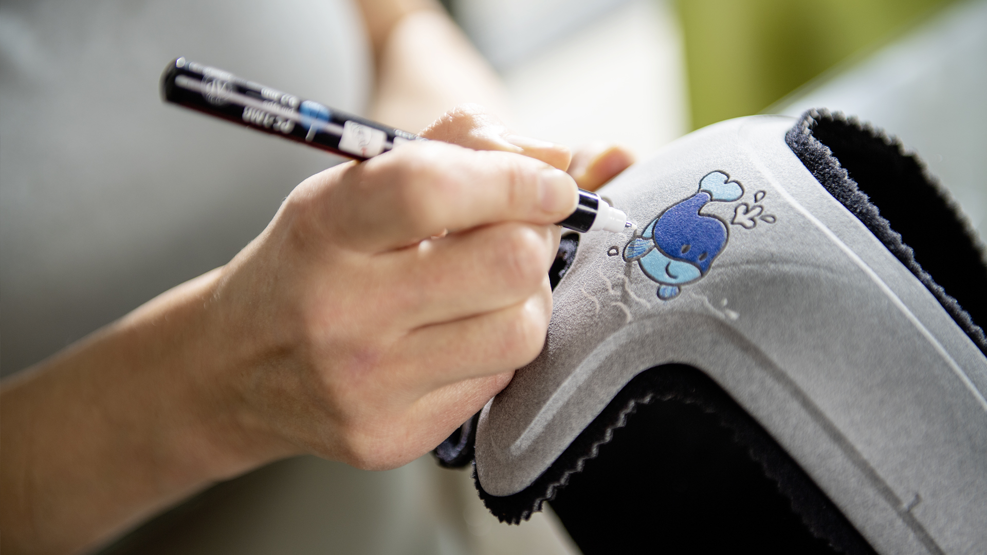 A parent drawing a whale on their child's MyCRO Band cranial helmet 