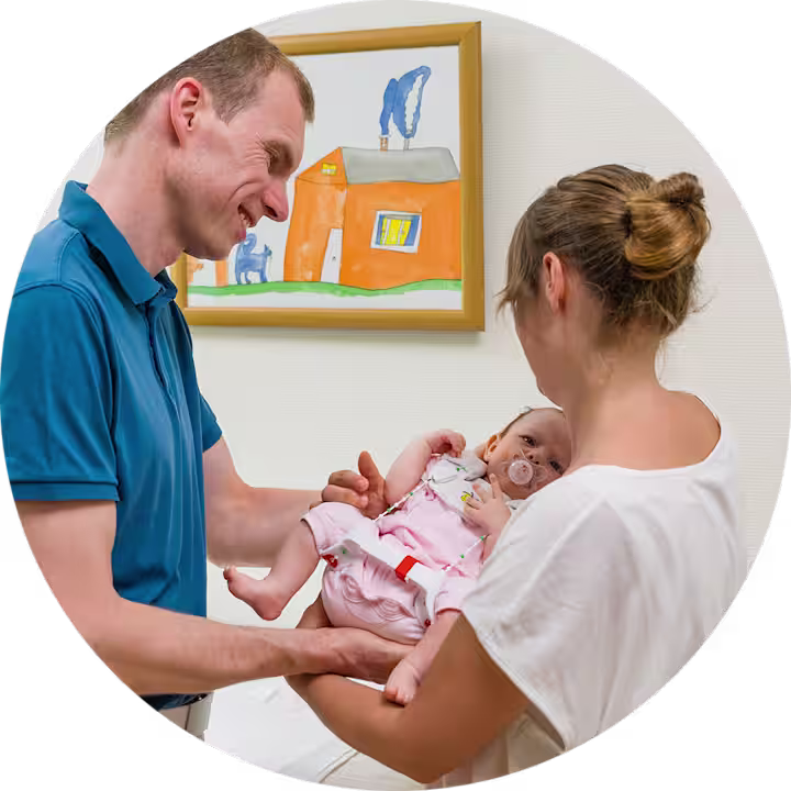 Eine Mutter hält ihr Kind auf dem Arm. Das Kind trägt aufgrund einer Hüftdysplasie eine Tübinger Hüftbeugeschiene von Ottobock.