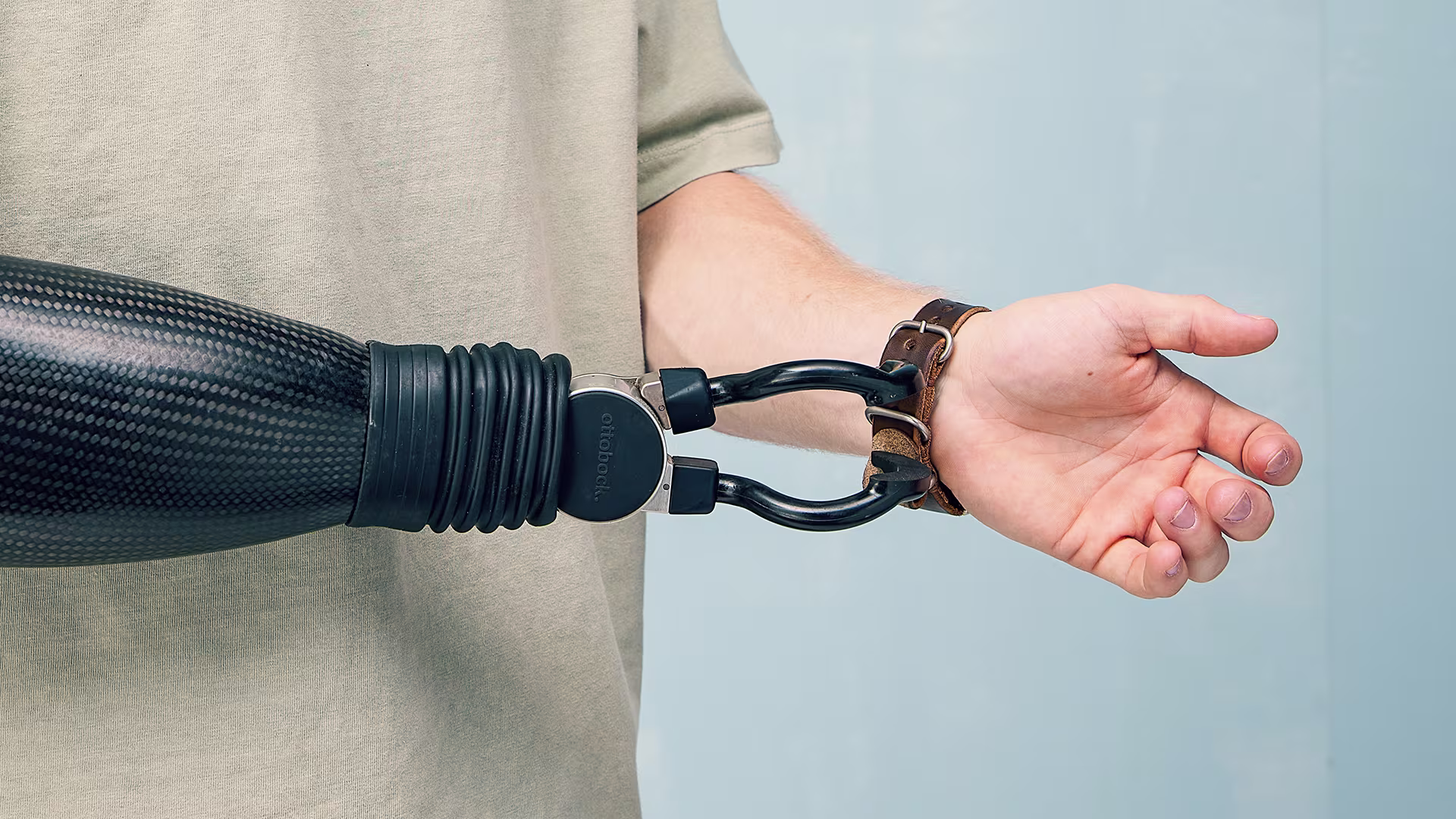A bionic hand tightens a watch on the user's left wrist