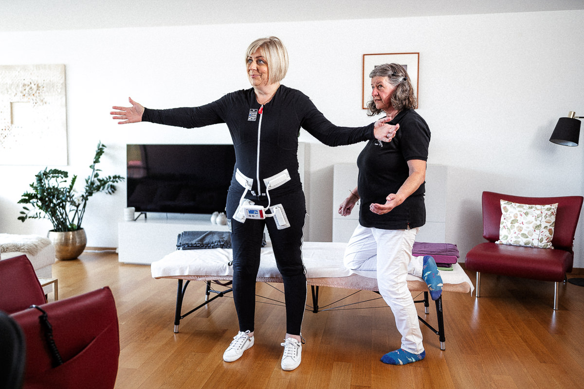 Jana steht frei im Raum während der Therapie mit der Kinesiologin. Sie lässt sich während der Therapie mit dem Exopulse Mollii Suit von Ottobock stimulieren. 