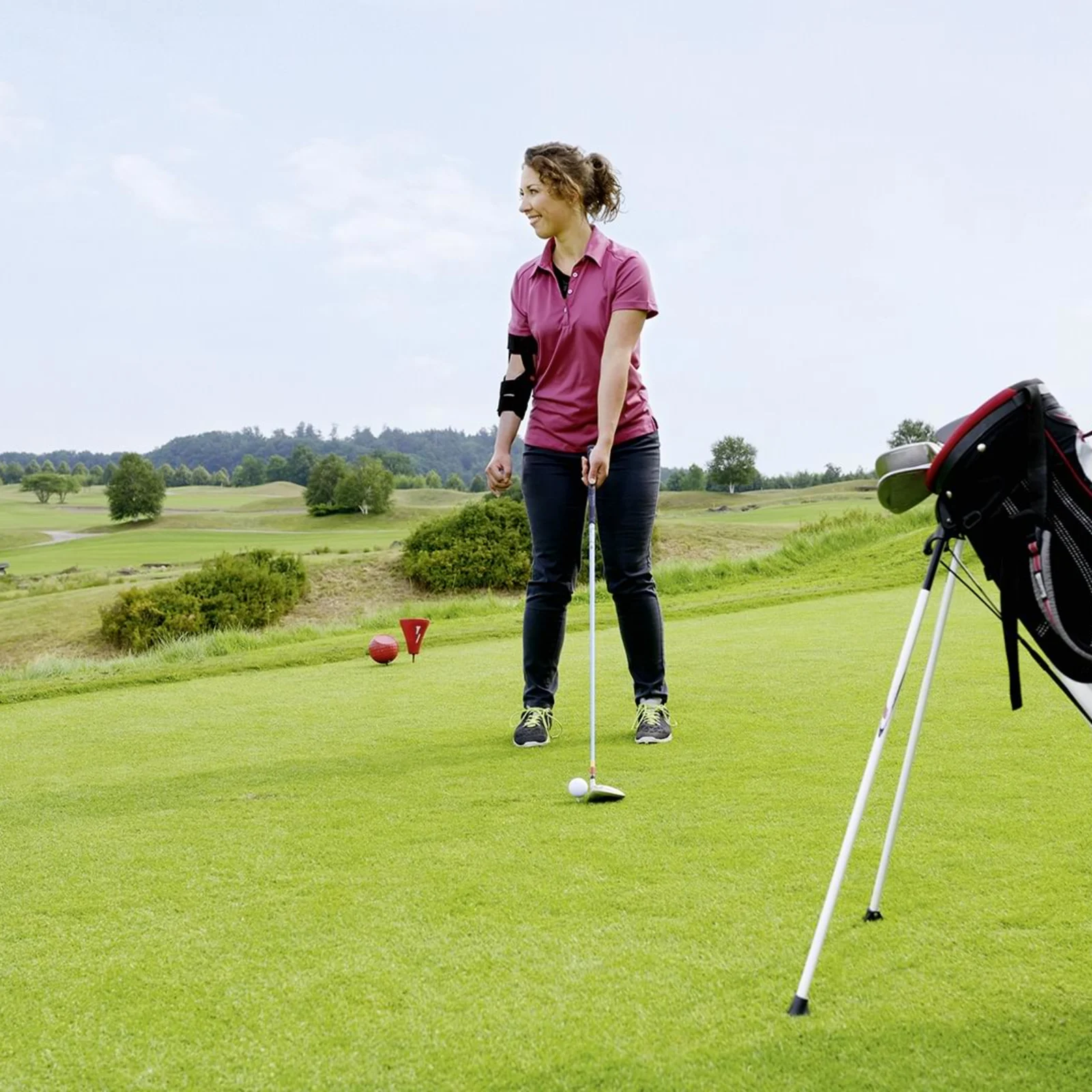 Девушка в плечевом ортезе Omo Neyrexa играет в гольф.