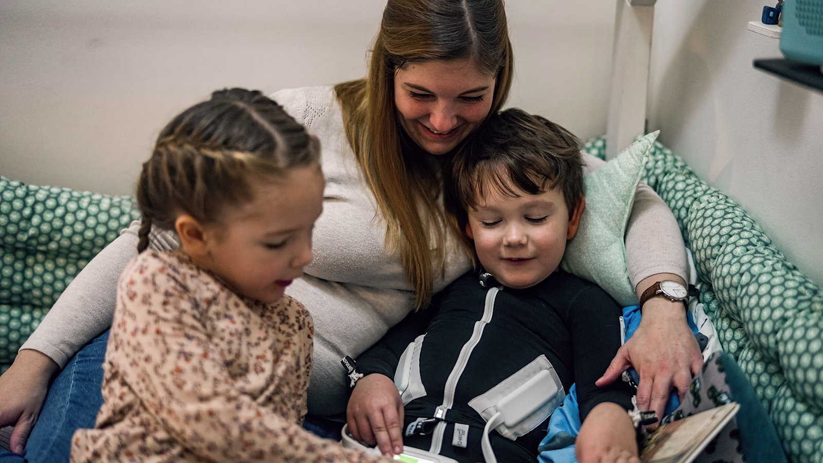 Cerebral palsy patient cuddling with his mother and sister