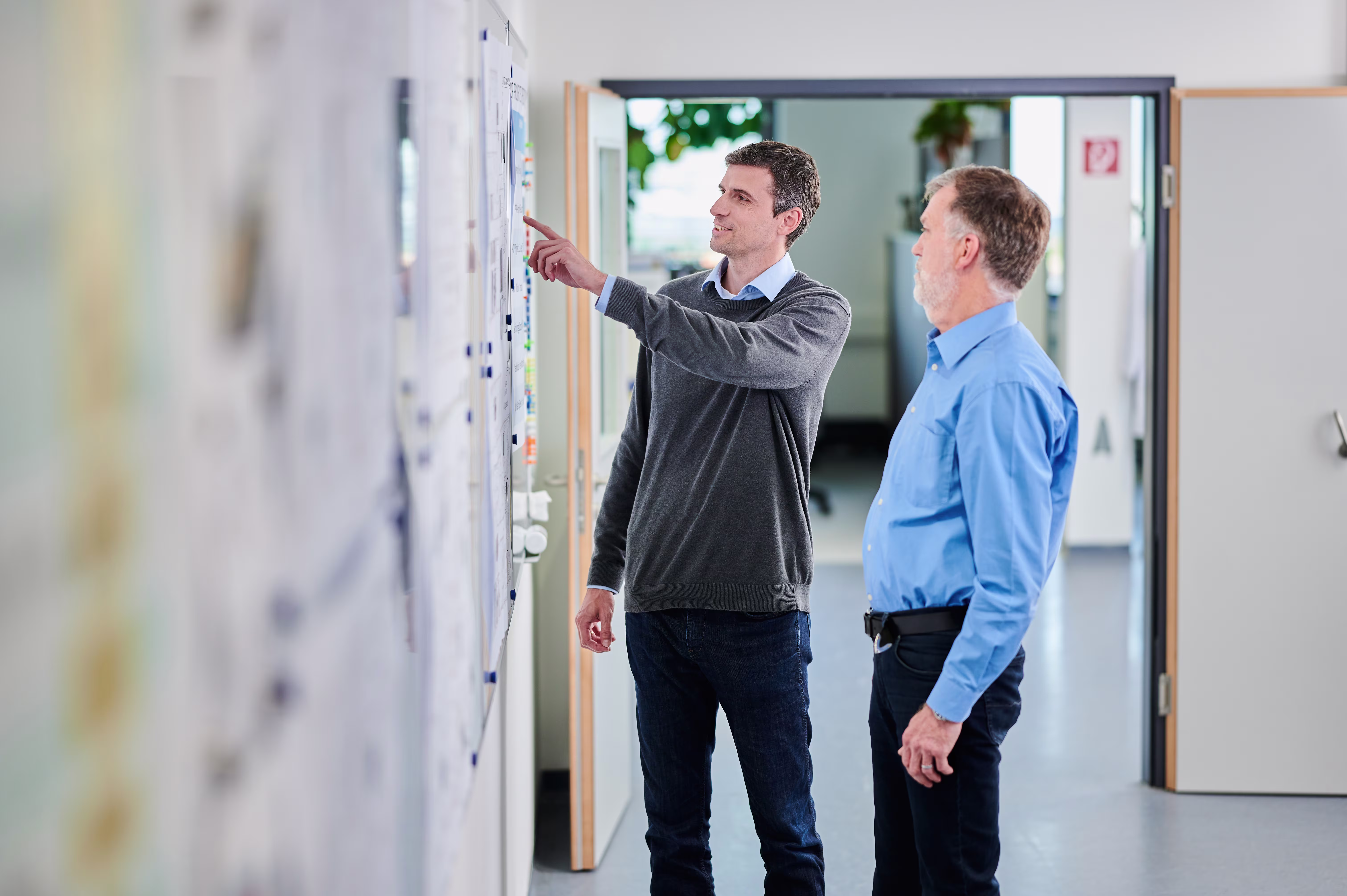 Two orthotic and prosthetic professionals discuss notes on a whiteboard