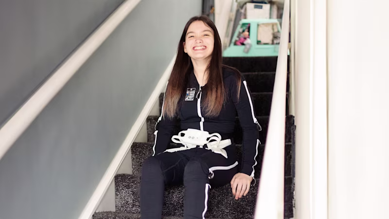 Cerebral Palsy patient wears Ottobock's Exopulse Molii Suit and is sitting on the stairs