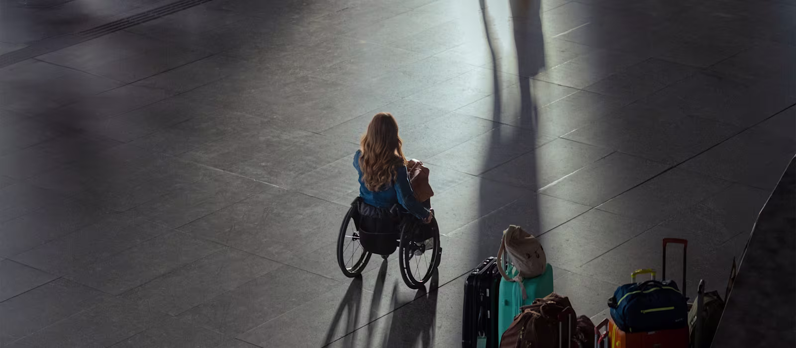 Traveler using a wheelchair moving across a station floor with luggage nearby, highlighting independence and the accessibility challenges featured in Ottobock’s Invisible Class campaign.