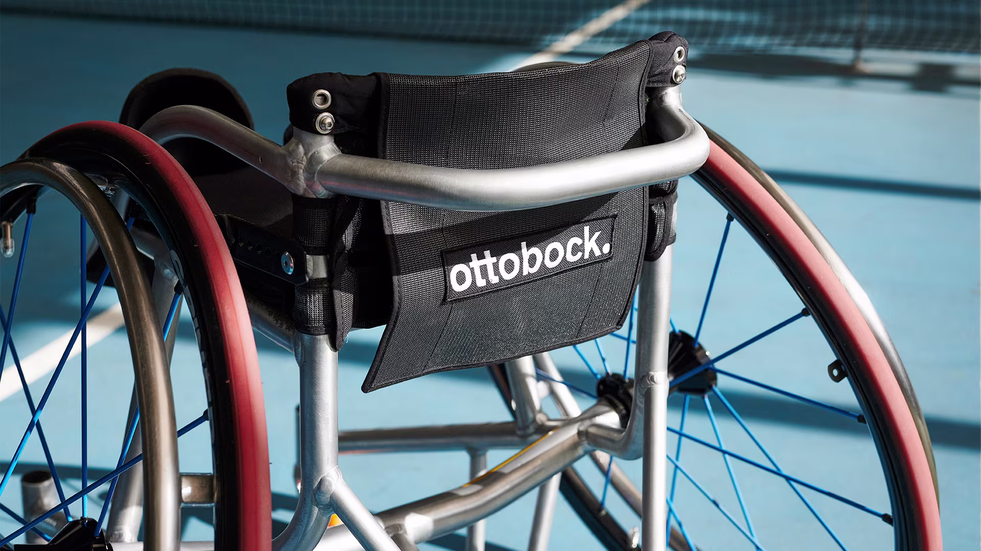 Close up of Ottobock logo on an Invader sports wheelchair standing on a tennis court