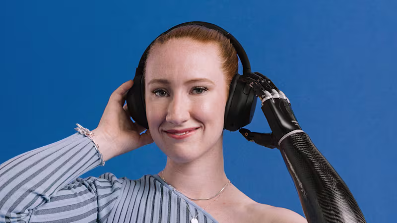Prosthetic arm user Enya with Ottobock bebionic hand listening to music, holding her headphones.