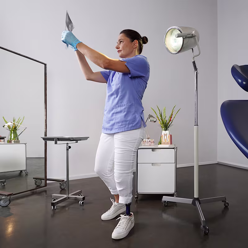 Eine Frau steht im Behandlungsraum einer Arztpraxis und schaut sich ein Röntgenbild an. Sie trägt den Prothesenfuß Evanto von Ottobock.