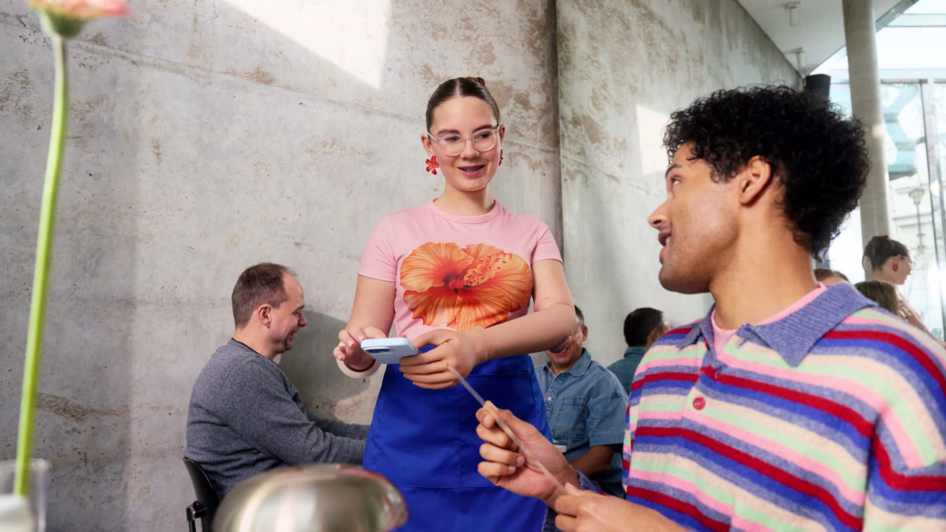 The picture shows a waitress wearing a michelangelo prosthetic hand who is taking the order of a customer.