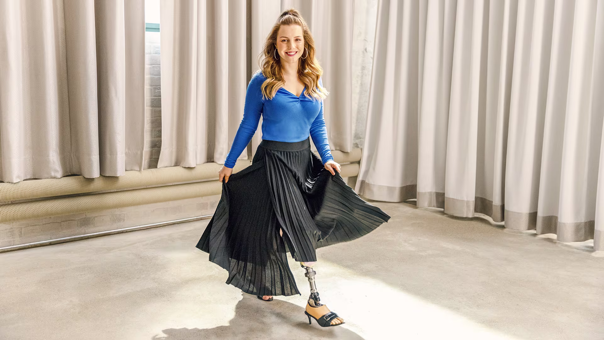 Woman modeling clothes with a smile, wearing her Ottobock Taleo Adjust prosthetic foot.