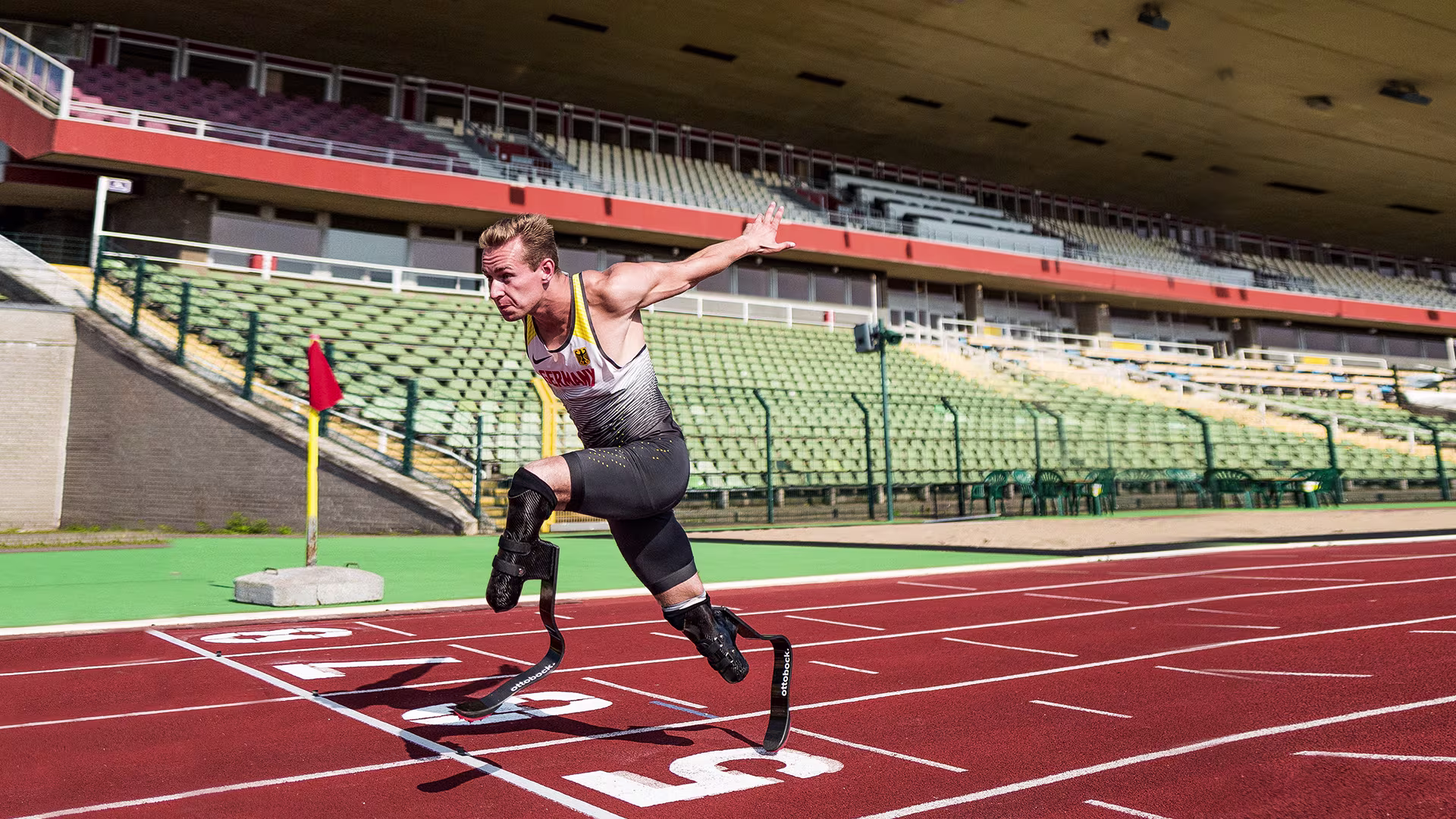 A bilateral amputee races to the finish line of a track field, sporting Ottobock's Runner prosthetic feet