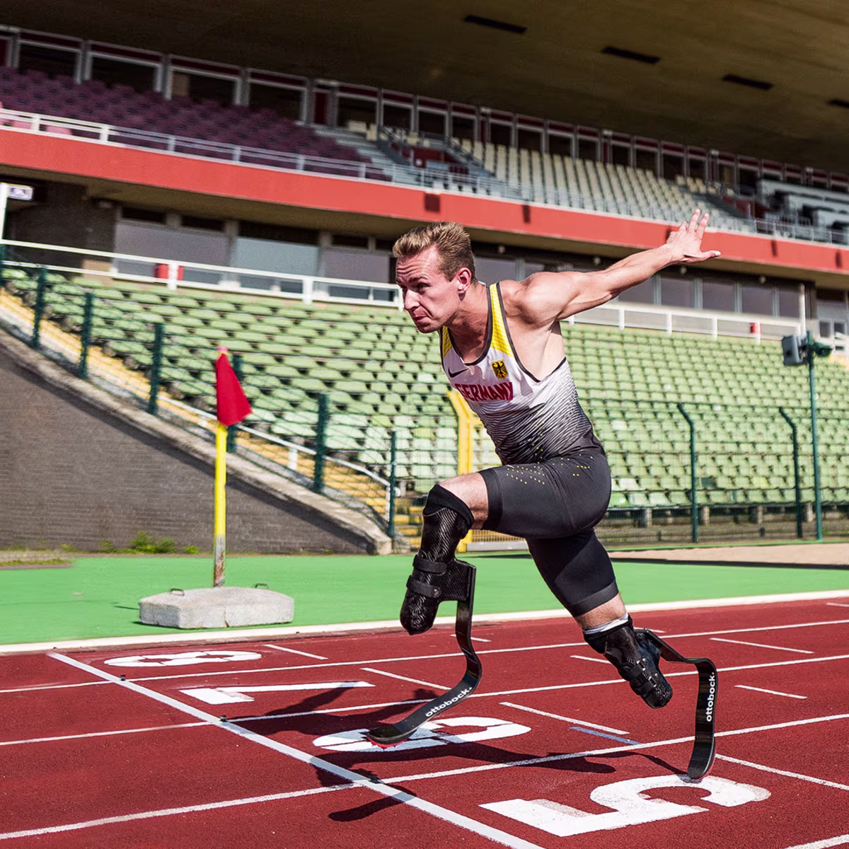A bilateral amputee races to the finish line of a track field, sporting Ottobock's Runner prosthetic feet