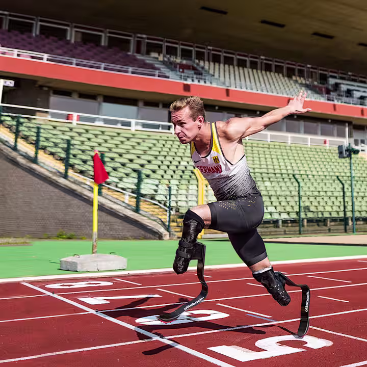 A bilateral amputee races to the finish line of a track field, sporting Ottobock's Runner prosthetic feet