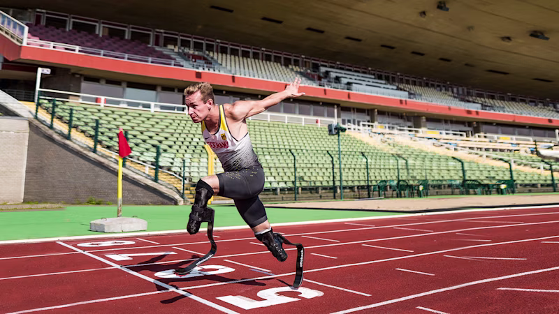 A bilateral amputee races to the finish line of a track field, sporting Ottobock's Runner prosthetic feet
