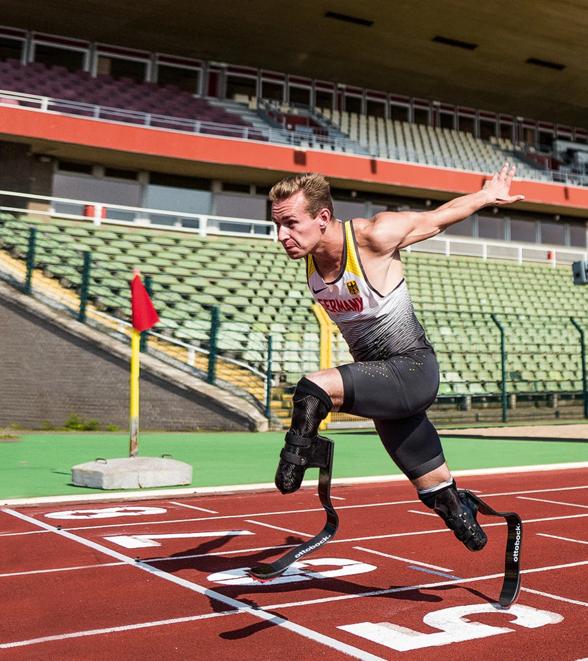 A bilateral amputee races to the finish line of a track field, sporting Ottobock's Runner prosthetic feet