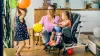 Emilia sitzt in einem Kimba Home und spielt mit ihrer Schwester und Mutter mit Luftballons