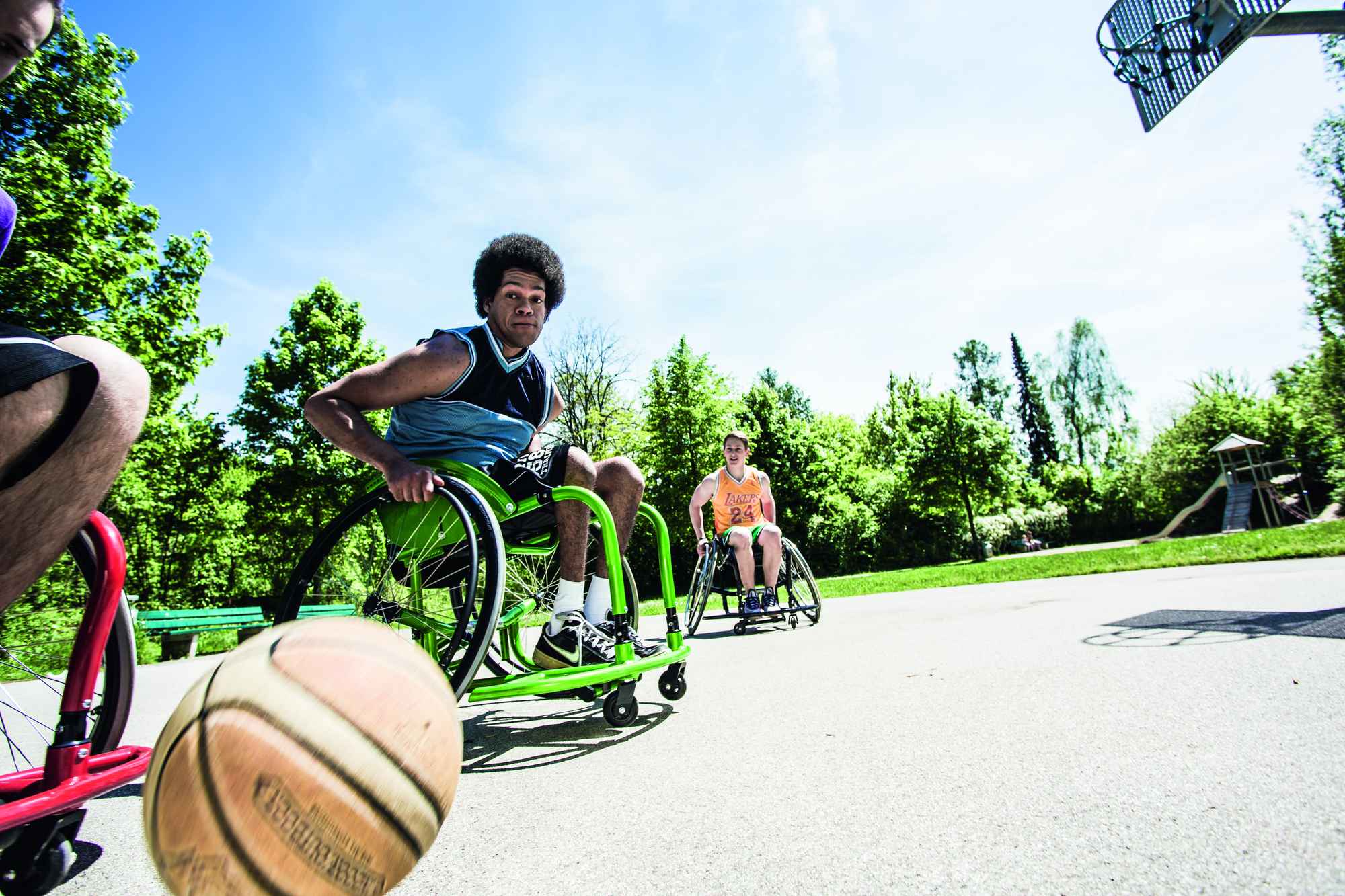 Low angle shot of a group of people playing outdoor wheelchair basketball