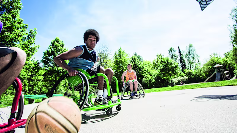 Low angle shot of a group of people playing outdoor wheelchair basketball