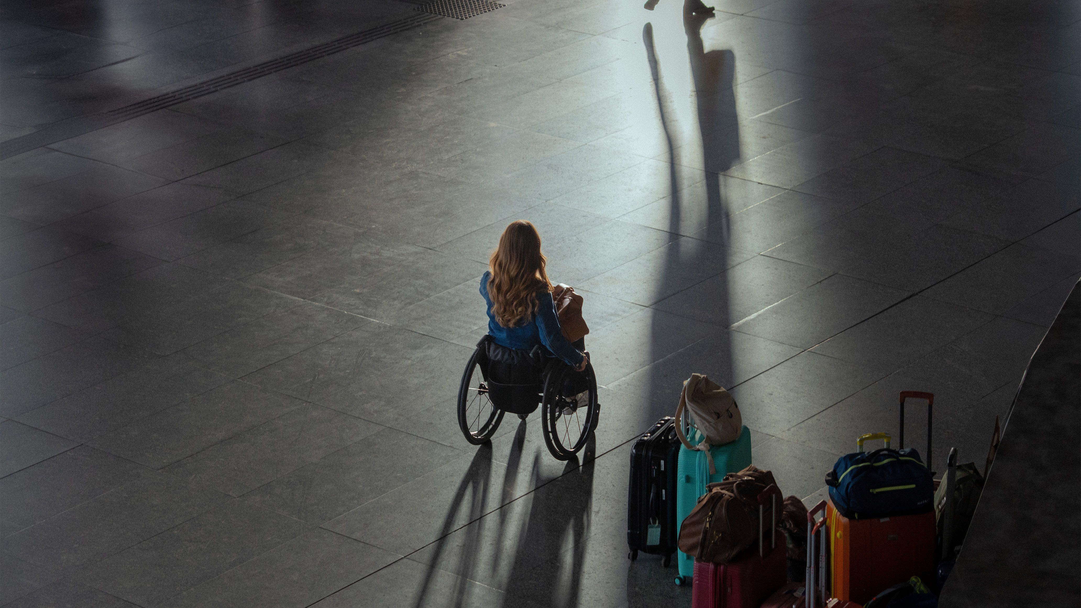 Traveler using a wheelchair moving across a station floor with luggage nearby, highlighting independence and the accessibility challenges featured in Ottobock’s Invisible Class campaign.