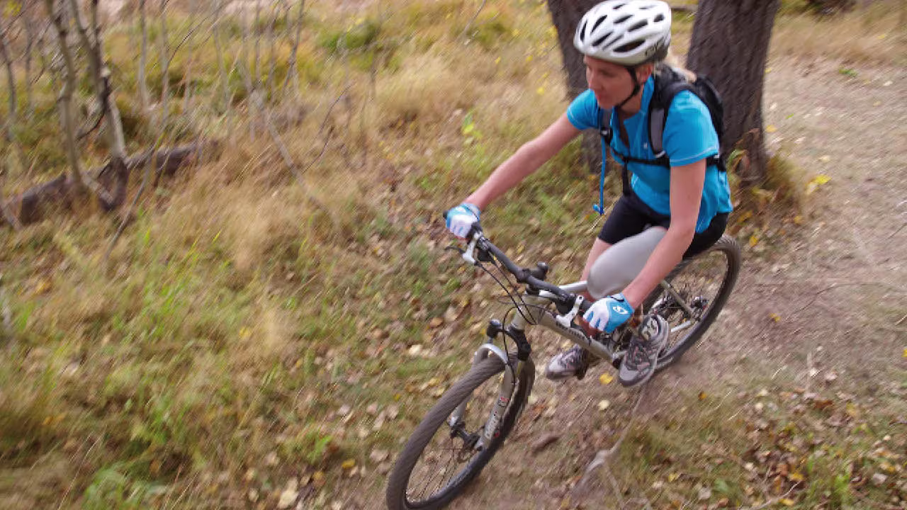Eine Prothesenträgerin fährt auf einem steilen Gelände Mountainbike. Sie trägt das mechatronische Prothesenkniegelenk Genium X4 von Ottobock.
