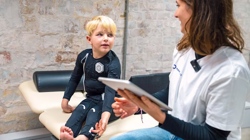A cerebral Palsy patient is sitting on a chair next to a physician
