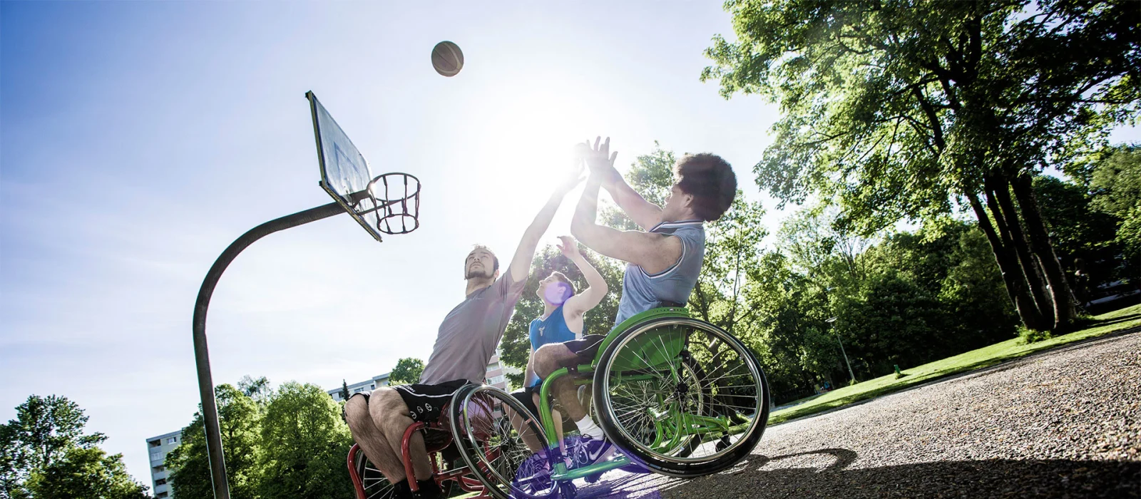 Ragazzi in carrozzina giocano a basket in un playground all'aperto