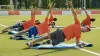 Atleti amputati fanno stretching su tappetini da yoga in un campo da calcio all'aperto