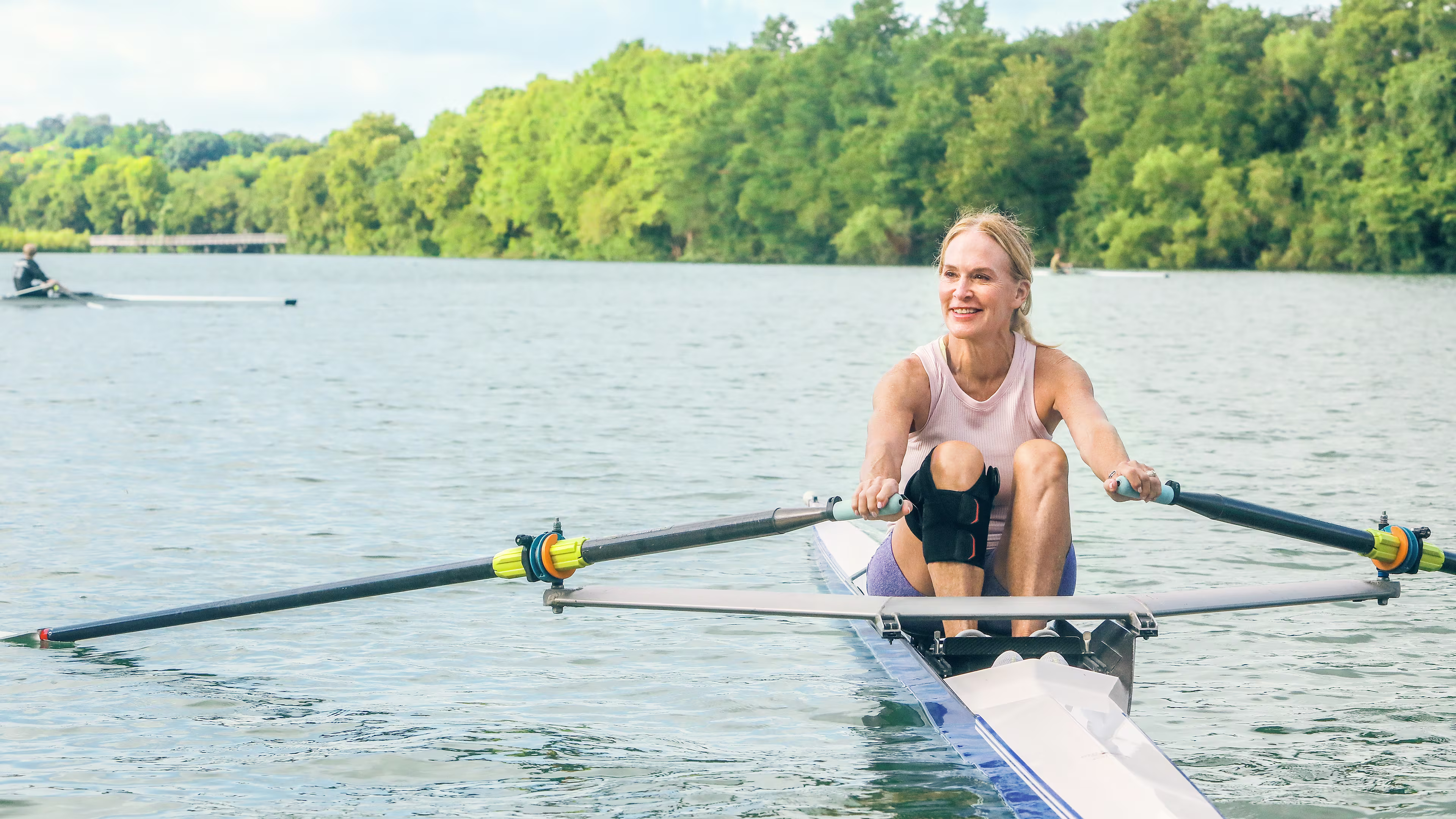 Eine weibliche Person sitzt auf einem Ruderboot auf dem See. Und trägt eine Agilium Vantage. 