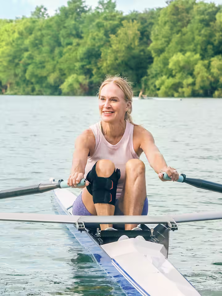 Eine weibliche Person sitzt auf einem Ruderboot auf dem See. Und trägt eine Agilium Vantage.