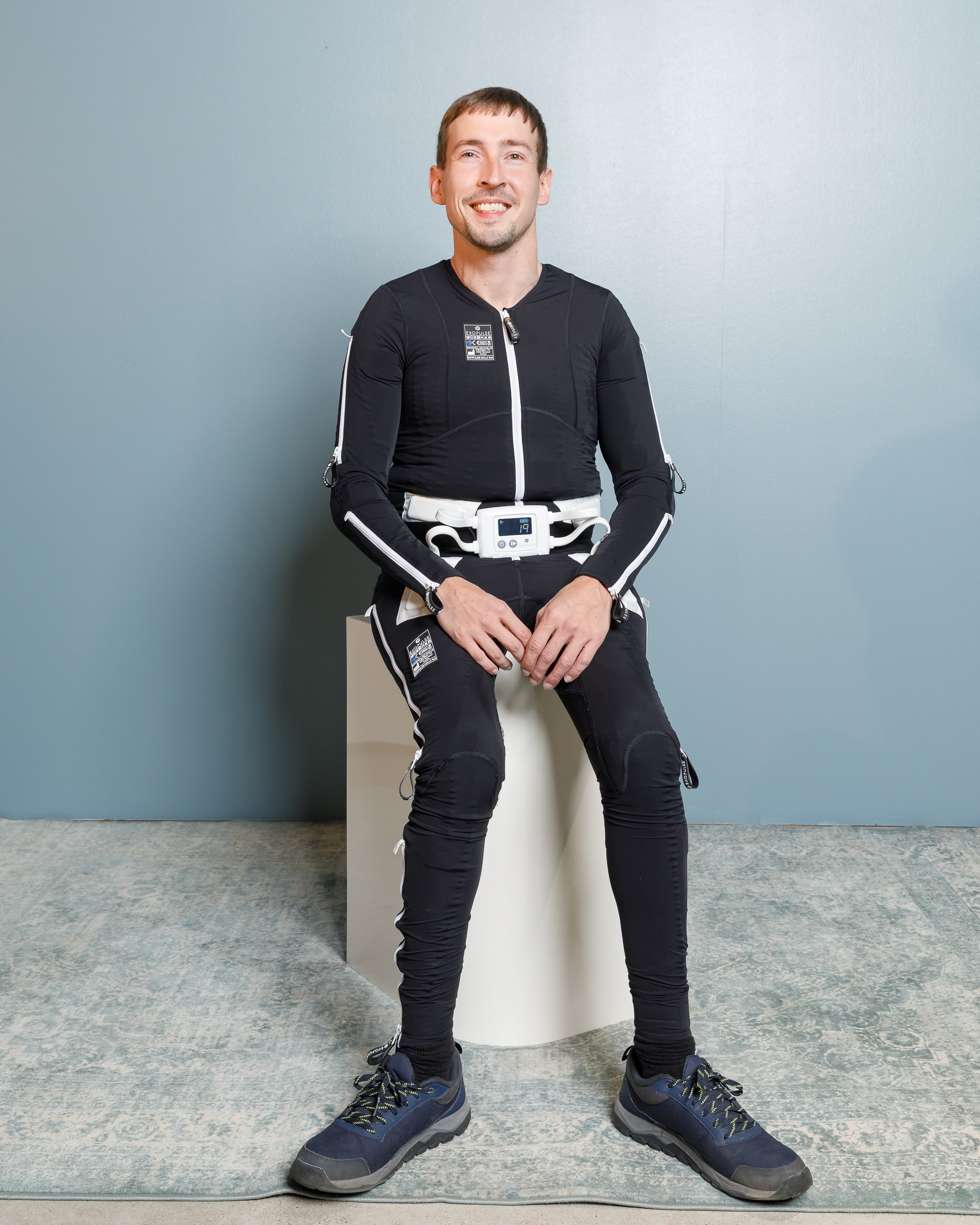 Cerebral Palsy patient Seffan wearing his Exopulse Mollii Suit sitting on a stool