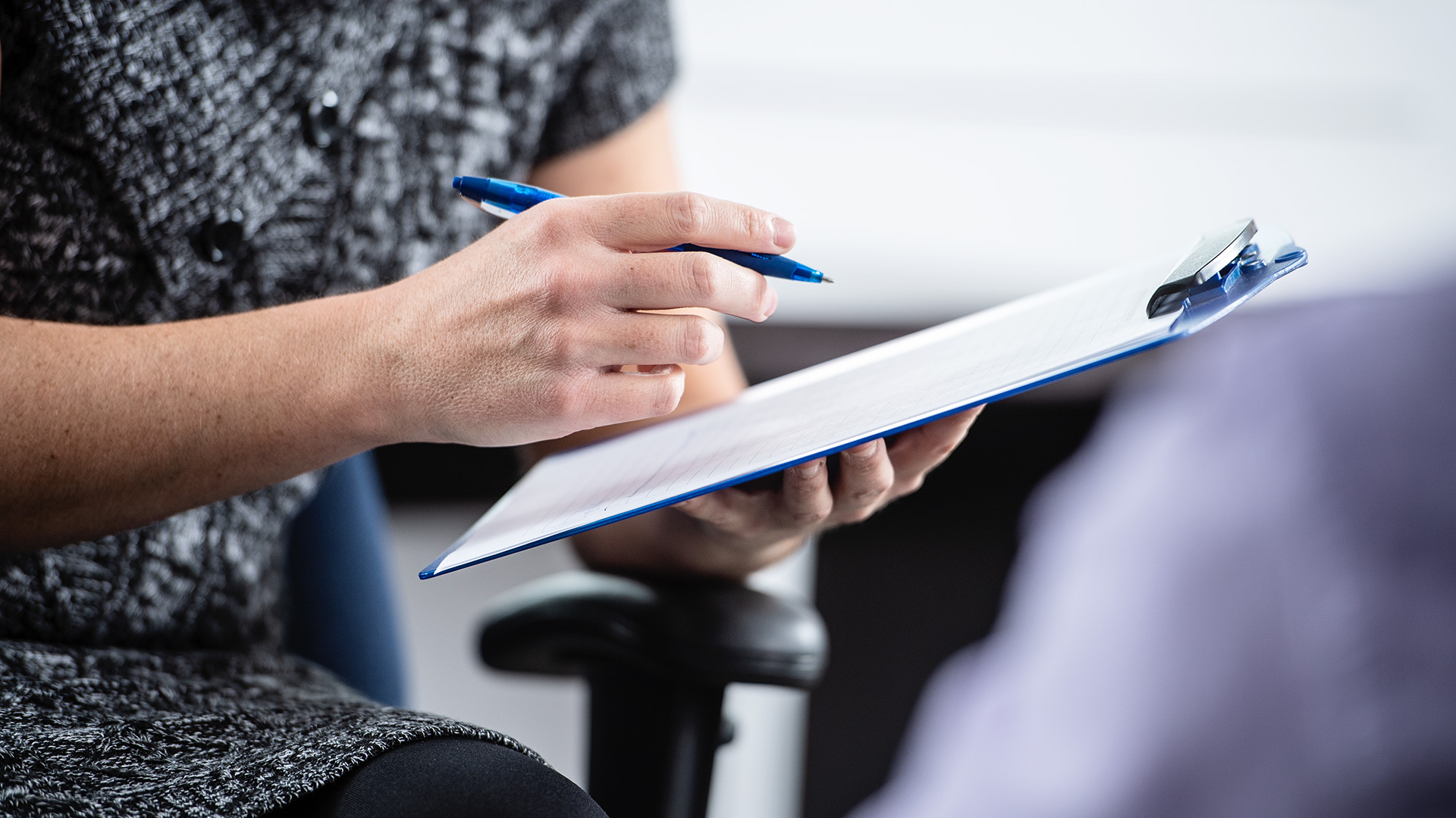 Close-up of a woman’s hands making notes in her notebook.
