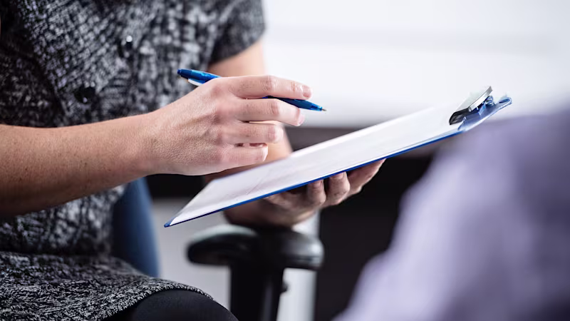 Close-up of a woman’s hands making notes in her notebook.