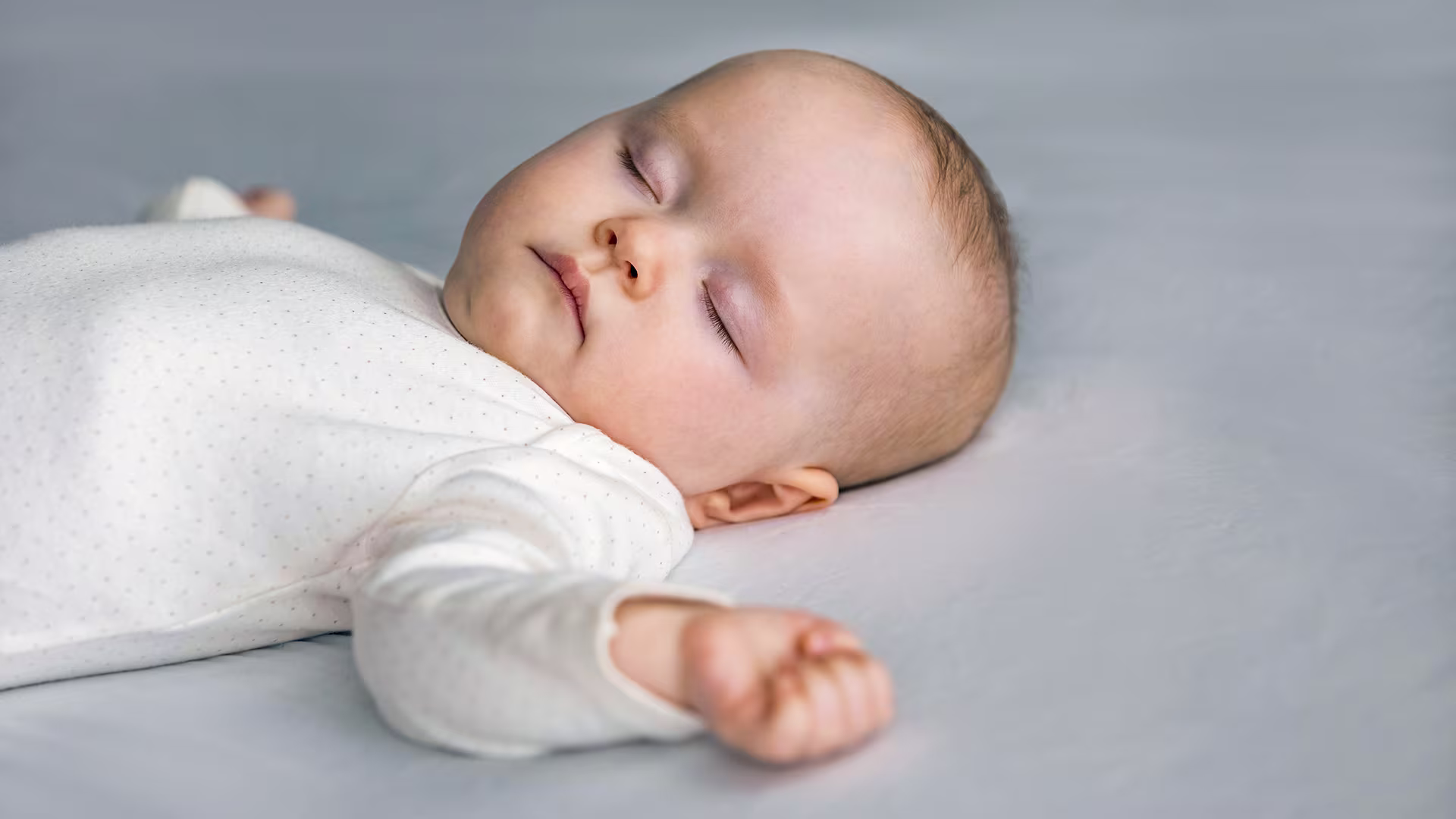 Baby sleeping on its back arms to its side