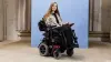 Power wheelchair user Kristina is in Ottobock Juvo B4, in front of a blue photo studio background.