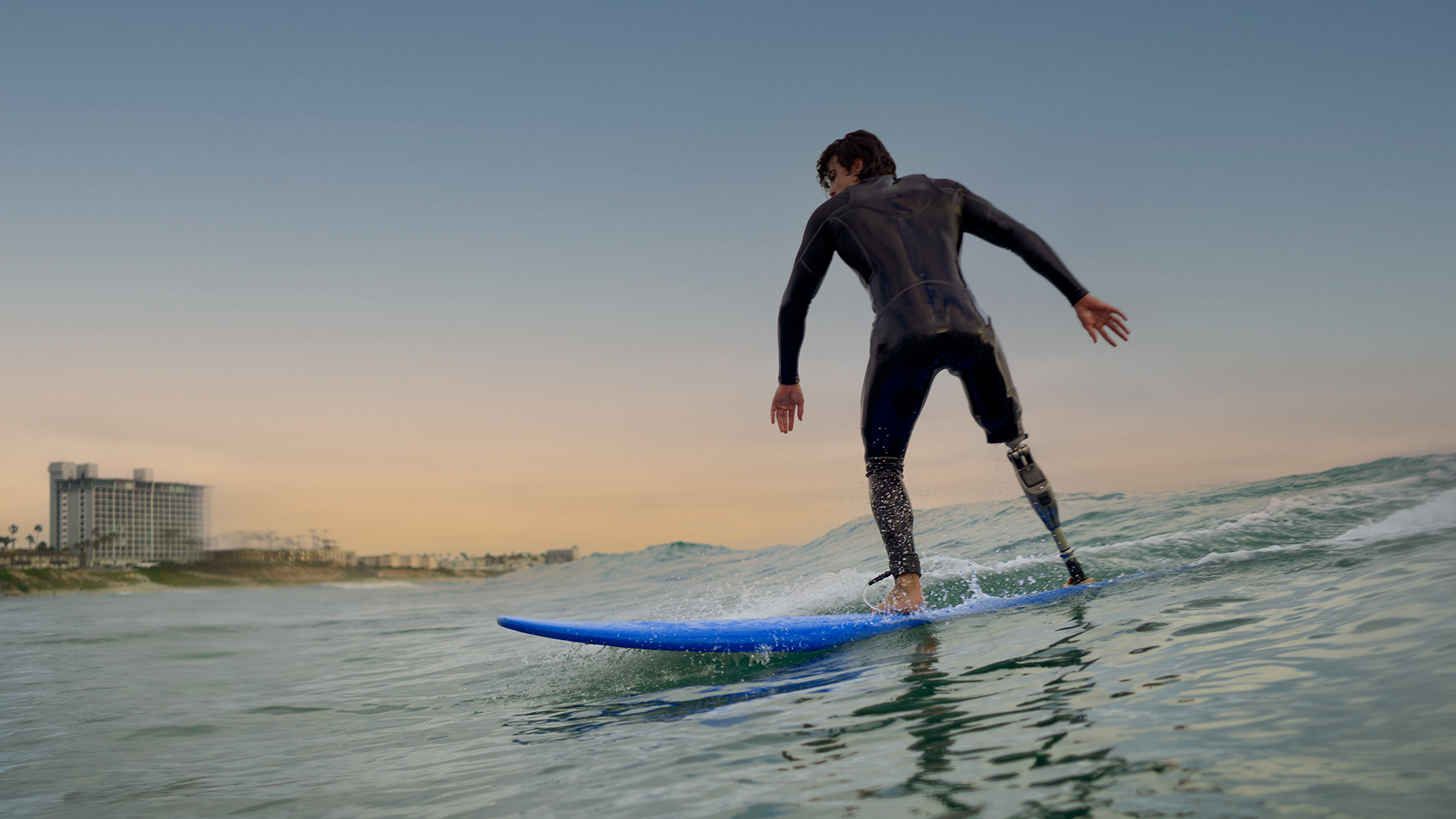A male surfer riding the waves while wearing his Ottobock Genium X4. 