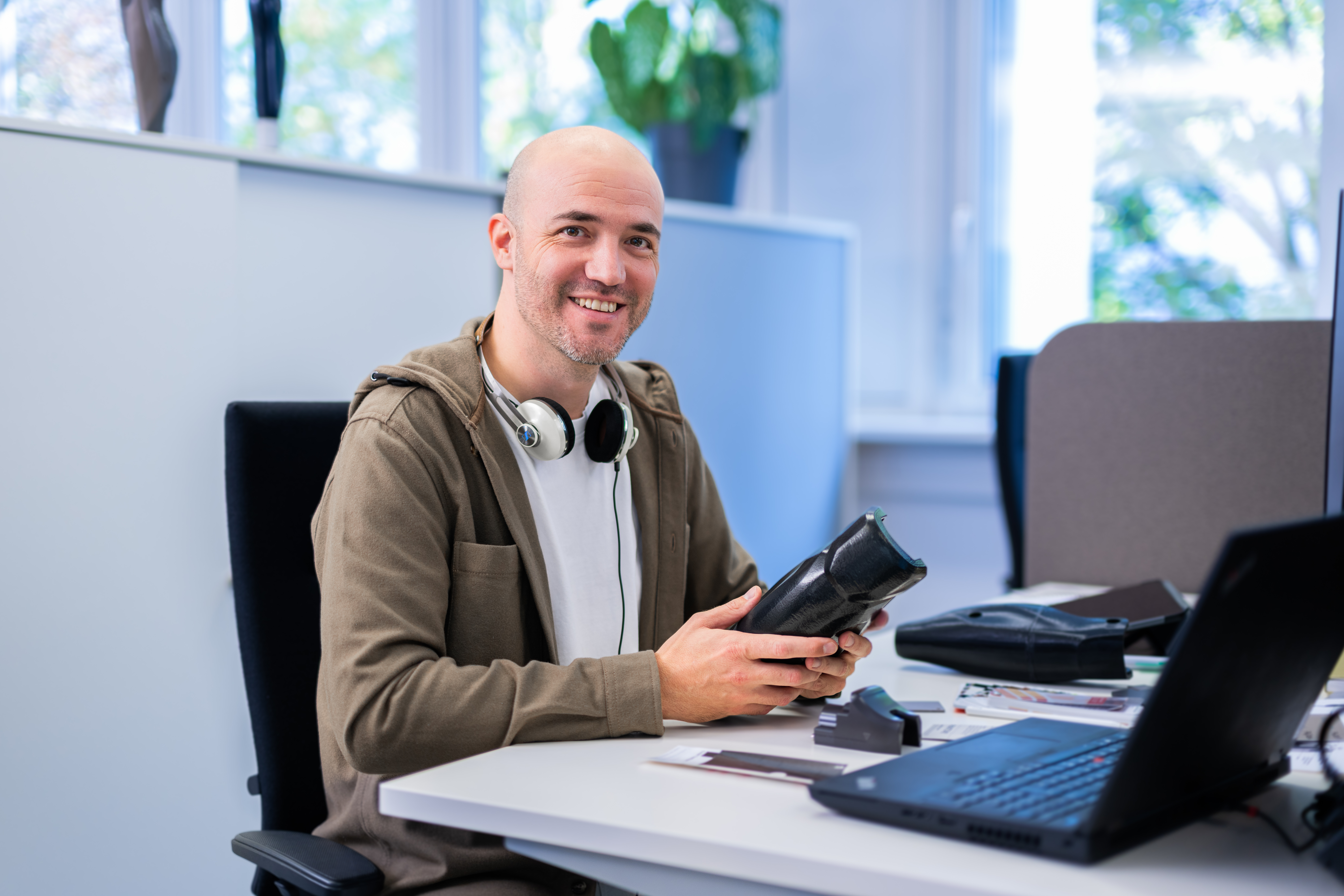 Auf dem Bild sieht man einen Ingenieur, der bei Ottobock arbeitet. Er hält einen Teil einer Prothese in der Hand und lächelt in die Kamera.