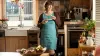 Женщина в коленном ортезе Agilium кушает у себя на кухне.