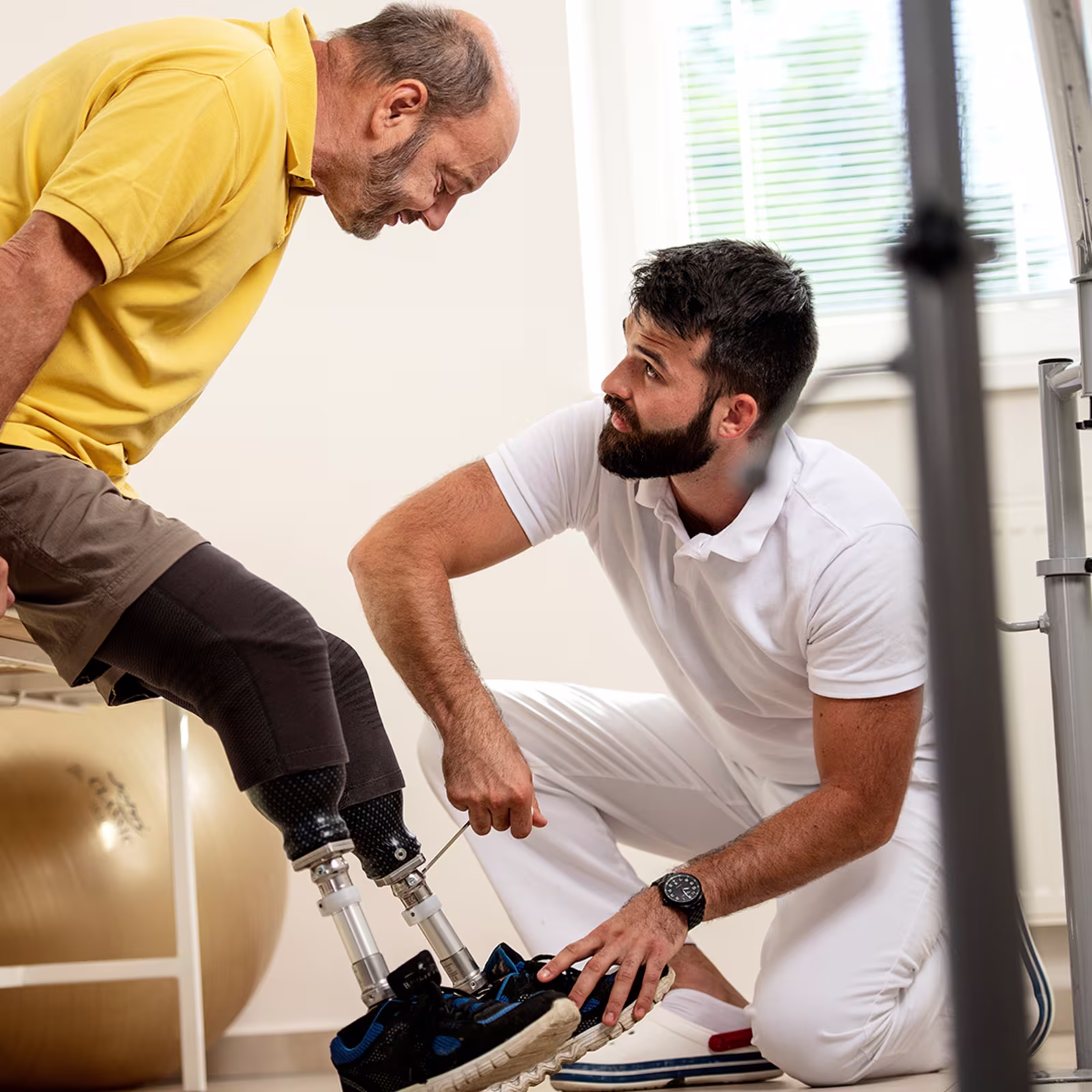 Ein Orthopädietechniker stellt mit Hilfe eines Imbusschlüssels das Prothesenkniegelenk eines Anwenders ein.