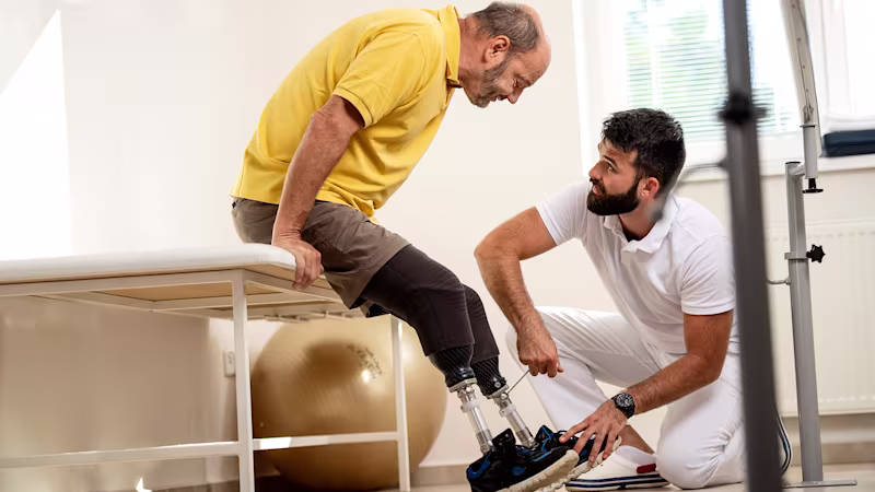 Ein Orthopädietechniker stellt mit Hilfe eines Imbusschlüssels das Prothesenkniegelenk eines Anwenders ein.