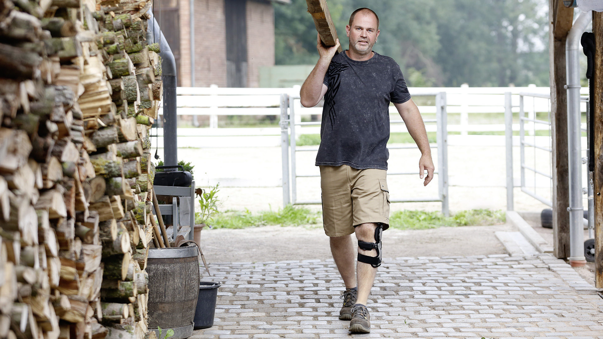Man with Ottobock Agilium Reactive Orthosis carries a wooden bar on his shoulder