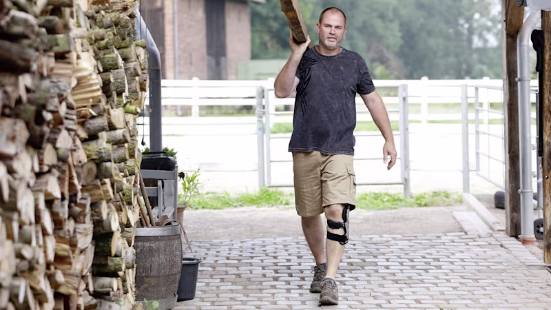 Man with Ottobock Agilium Reactive Orthosis carries a wooden bar on his shoulder