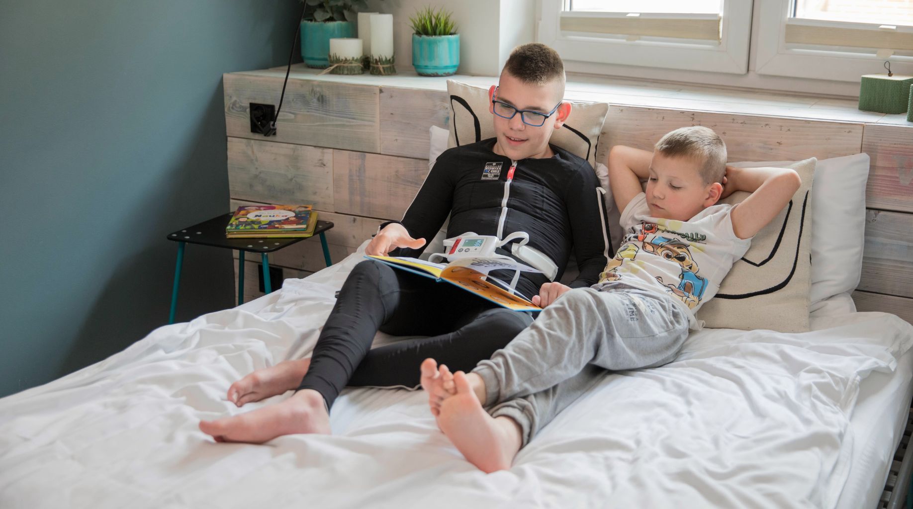 Czytanie książki na łóżku podczas stymulacji kombinezonem Exopulse Mollii Suit.