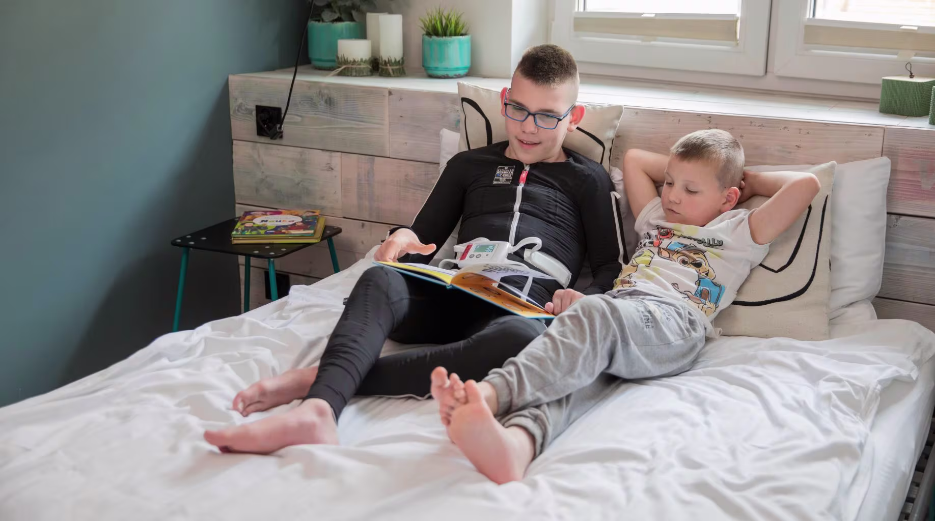 Czytanie książki na łóżku podczas stymulacji kombinezonem Exopulse Mollii Suit.