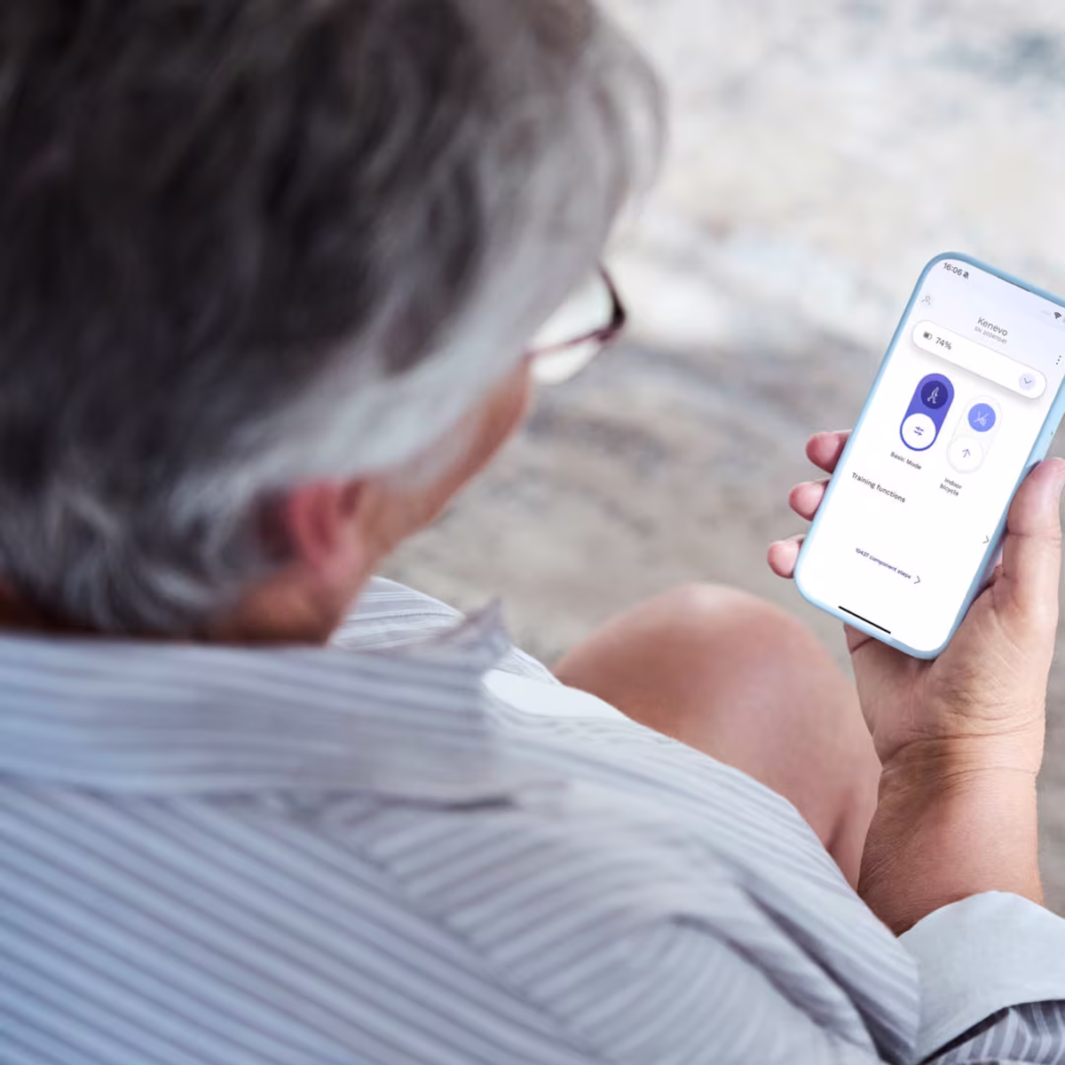 A shoulder view of a person holding a smartphone and using the Ottobock connectpro app.