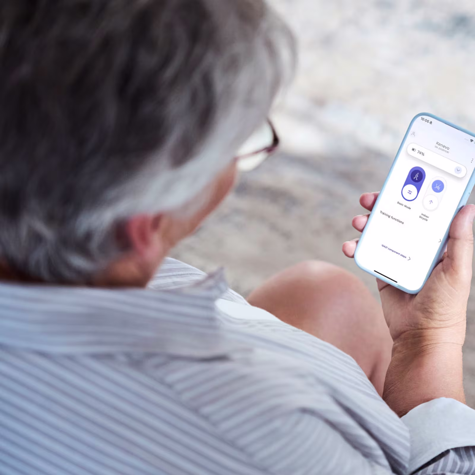 A shoulder view of a person holding a smartphone and using the Ottobock connectpro app.
