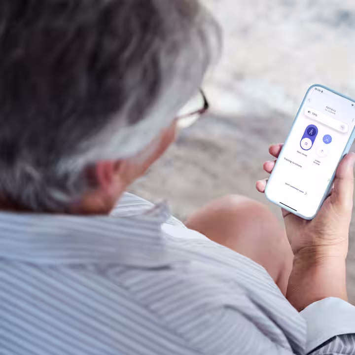 A shoulder view of a person holding a smartphone and using the Ottobock connectpro app.